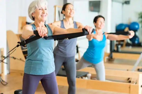 Toning Arms After 60: Empowering Womens Fitness Through Effective Weight Training 2 older woman doing weight training Eastbourne and resistance in the gym to tone upper arms