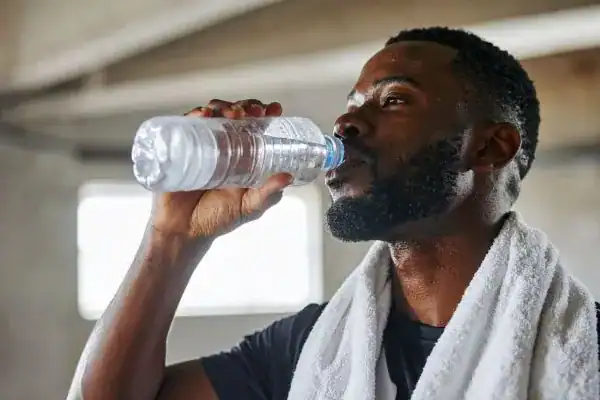Image of man drinking water to improve hydration Eastbourne after work out.